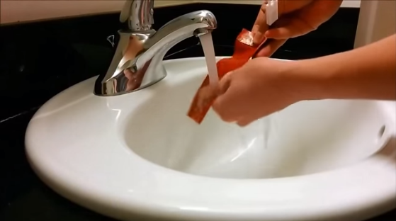 Running water and soap over a penis extender to clean it.